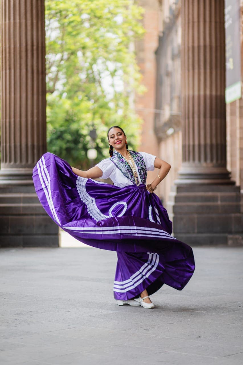 Bailarina de danza folklórica con traje regional entre las columnas del Teatro de la Paz